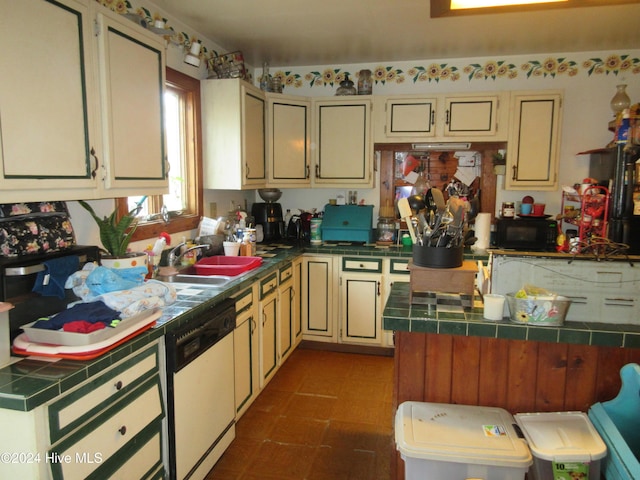 kitchen with tile countertops, cream cabinets, sink, and white dishwasher