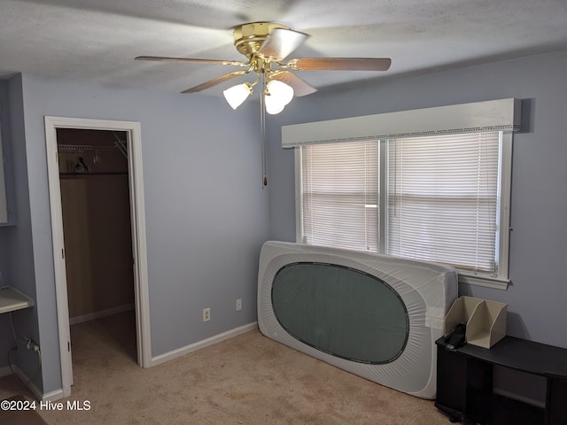 living area with a textured ceiling, ceiling fan, and light carpet