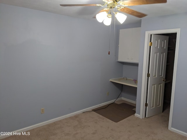 unfurnished office featuring ceiling fan and light colored carpet