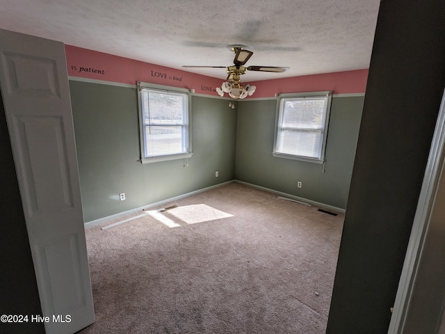 empty room featuring carpet, ceiling fan, and a textured ceiling