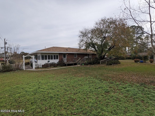 rear view of house with a deck and a yard