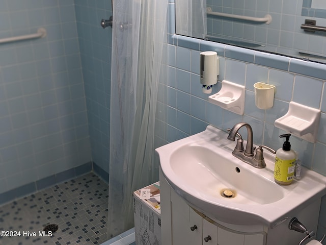 bathroom featuring decorative backsplash, a tile shower, tile walls, and vanity