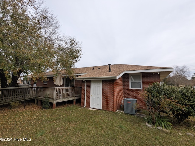 back of house with central AC unit, a deck, and a yard