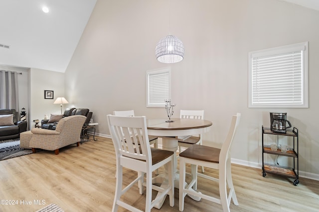 dining room featuring high vaulted ceiling and light hardwood / wood-style flooring