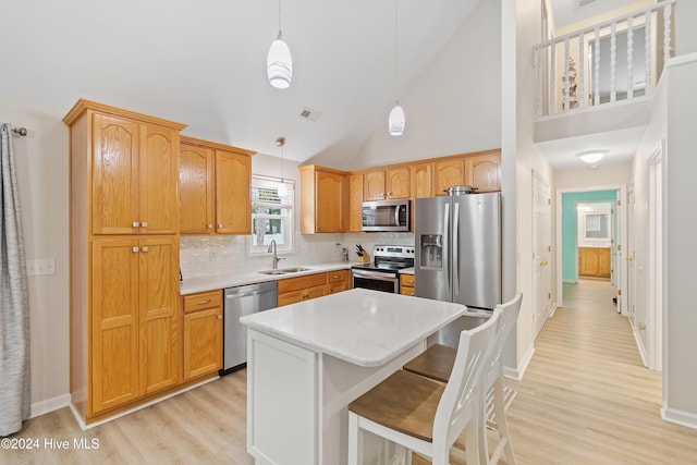 kitchen with hanging light fixtures, high vaulted ceiling, stainless steel appliances, and a kitchen island