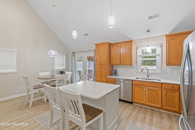 kitchen with sink, high vaulted ceiling, stainless steel appliances, and decorative light fixtures