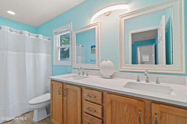 bathroom featuring wood-type flooring, vanity, toilet, and walk in shower