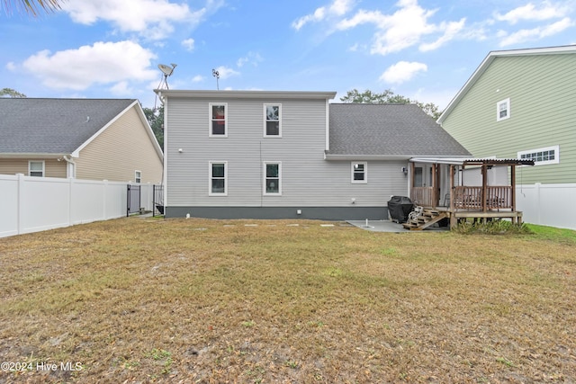 rear view of house with a wooden deck and a yard