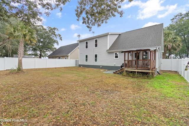 back of property with a yard and a wooden deck