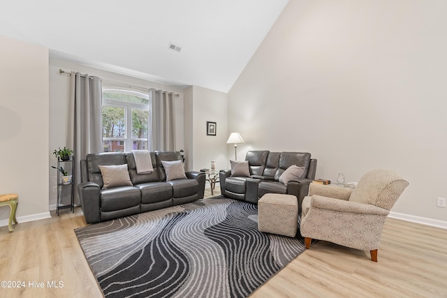 living room with light hardwood / wood-style flooring and high vaulted ceiling