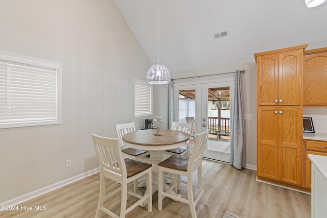 dining area featuring light hardwood / wood-style flooring, high vaulted ceiling, and french doors