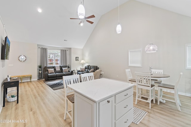 kitchen with high vaulted ceiling, ceiling fan, a kitchen island, light hardwood / wood-style floors, and white cabinetry