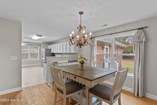 dining area featuring ceiling fan with notable chandelier and light hardwood / wood-style floors