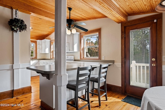 kitchen with white cabinetry, vaulted ceiling with beams, a kitchen breakfast bar, wood ceiling, and kitchen peninsula