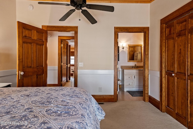 bedroom featuring ceiling fan, sink, light carpet, and ensuite bath