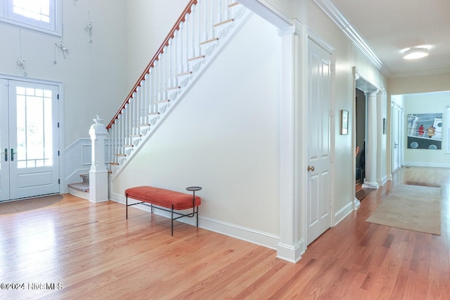 entryway featuring light hardwood / wood-style floors, ornamental molding, and ornate columns