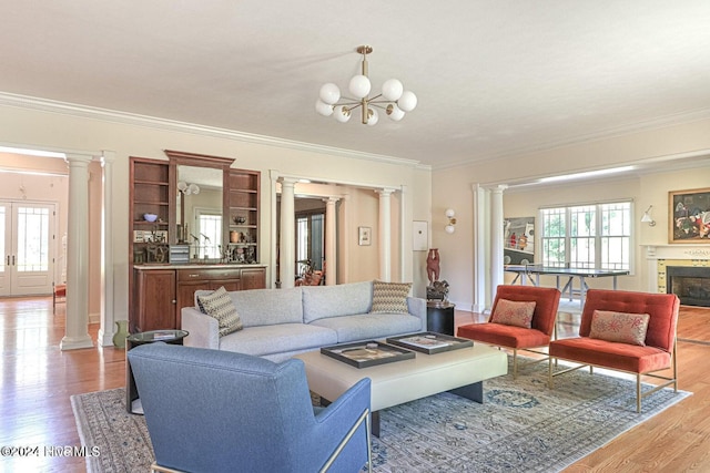 215 Inverrary Rd, Pinehurst, NC 28374 - living room with ornate columns, ornamental molding, wood finished floors, a fireplace, and a chandelier