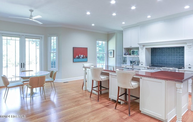 kitchen featuring white cabinetry, a wealth of natural light, light hardwood / wood-style flooring, and a kitchen island with sink