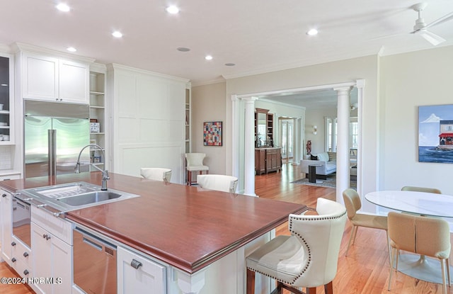 kitchen with white cabinets, ornate columns, appliances with stainless steel finishes, and light hardwood / wood-style flooring