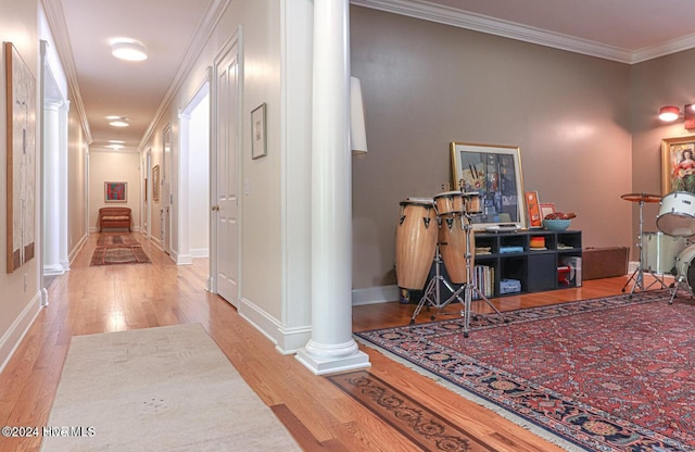 corridor featuring light hardwood / wood-style floors, ornate columns, and crown molding