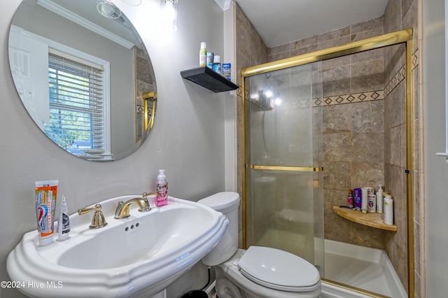 bathroom with ornamental molding, sink, toilet, and a shower with shower door