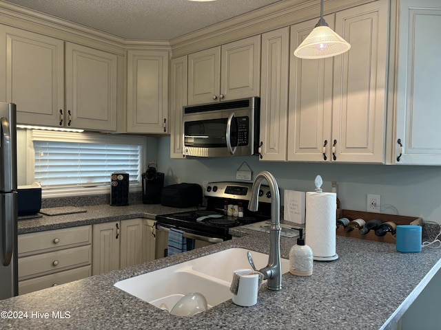 kitchen featuring cream cabinetry, a textured ceiling, stainless steel appliances, and hanging light fixtures