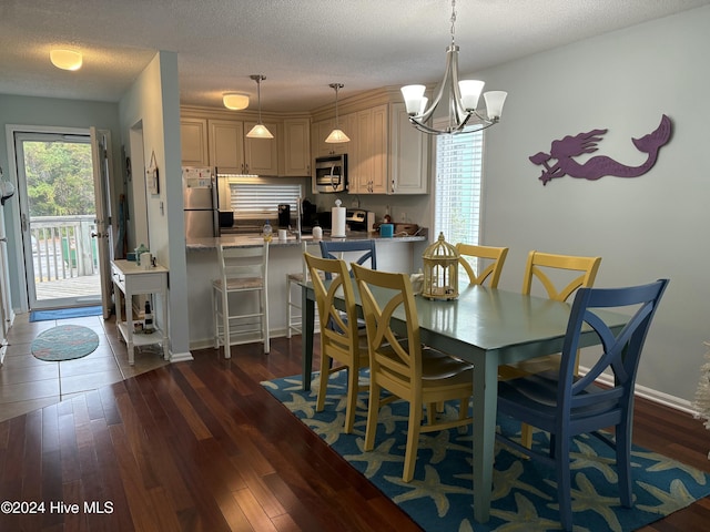 dining space featuring a chandelier, a textured ceiling, and dark hardwood / wood-style flooring