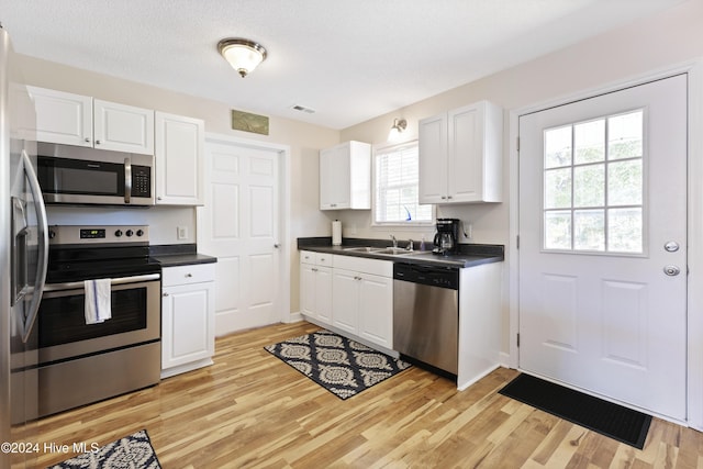 kitchen featuring white cabinets, sink, a textured ceiling, appliances with stainless steel finishes, and light hardwood / wood-style floors