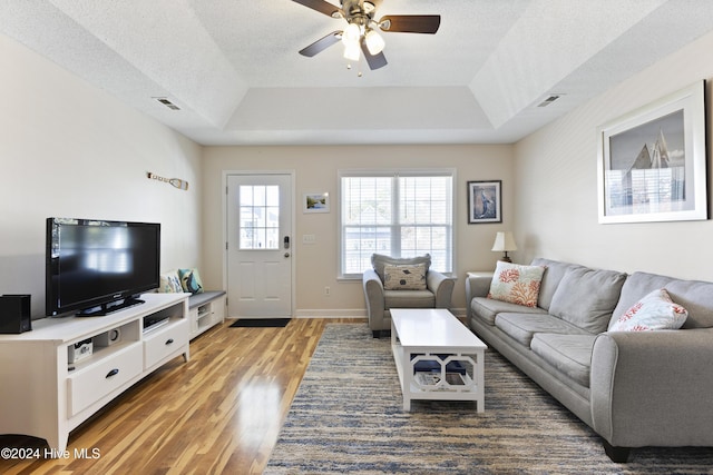 living room with a textured ceiling, dark hardwood / wood-style flooring, and a tray ceiling