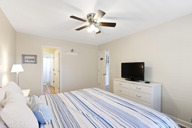 bedroom with light hardwood / wood-style floors, ensuite bath, and ceiling fan