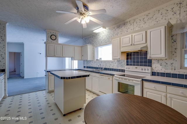 kitchen with a textured ceiling, white appliances, ceiling fan, sink, and tile countertops