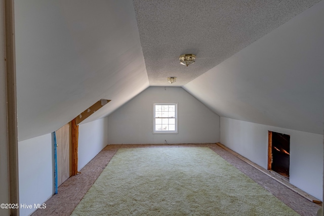 bonus room with light colored carpet, lofted ceiling, and a textured ceiling