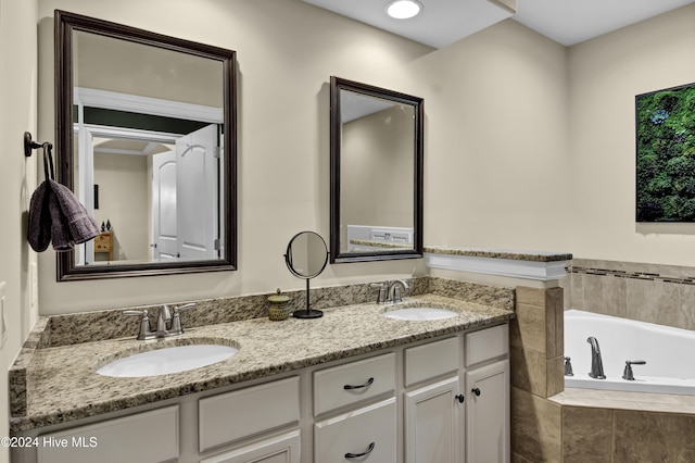 bathroom featuring tiled tub and vanity