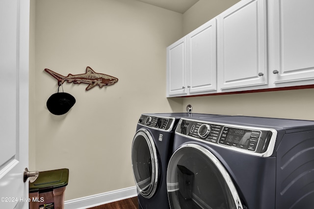 clothes washing area featuring cabinets, washer and clothes dryer, and dark hardwood / wood-style flooring