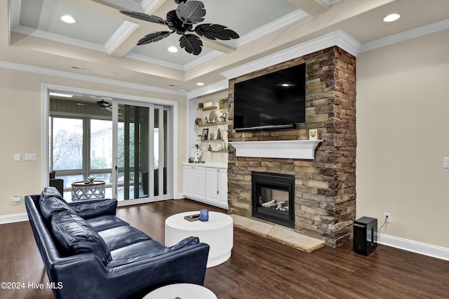 living room with a stone fireplace, beam ceiling, ornamental molding, ceiling fan, and dark hardwood / wood-style floors