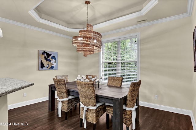 dining space with dark hardwood / wood-style floors, a tray ceiling, and ornamental molding