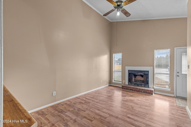 unfurnished living room featuring a fireplace, light hardwood / wood-style floors, ceiling fan, and crown molding