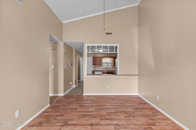 interior space featuring hardwood / wood-style floors, high vaulted ceiling, and ornamental molding