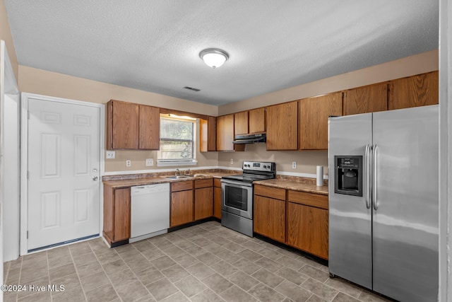 kitchen with a textured ceiling, sink, and appliances with stainless steel finishes