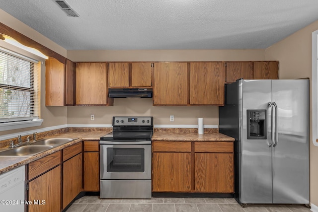 kitchen featuring a textured ceiling, light tile patterned flooring, sink, and appliances with stainless steel finishes