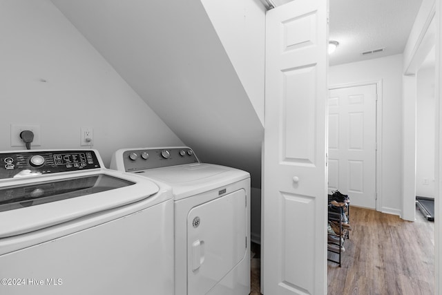 laundry room featuring light hardwood / wood-style floors, independent washer and dryer, and a textured ceiling