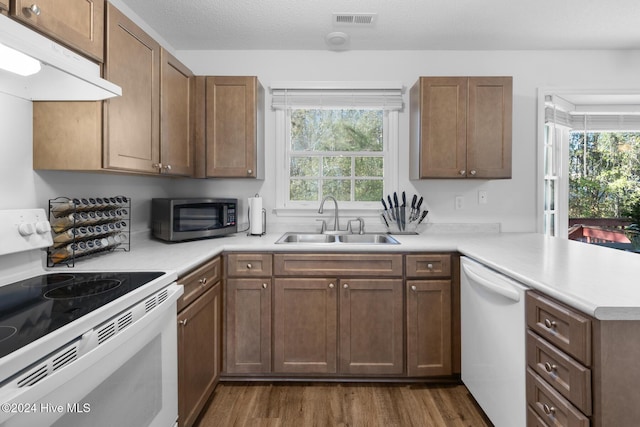 kitchen with kitchen peninsula, dark hardwood / wood-style flooring, white appliances, a textured ceiling, and sink