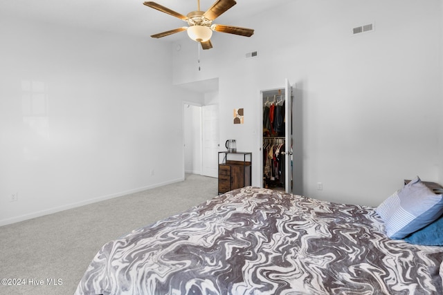 carpeted bedroom featuring ceiling fan, a walk in closet, a high ceiling, and a closet