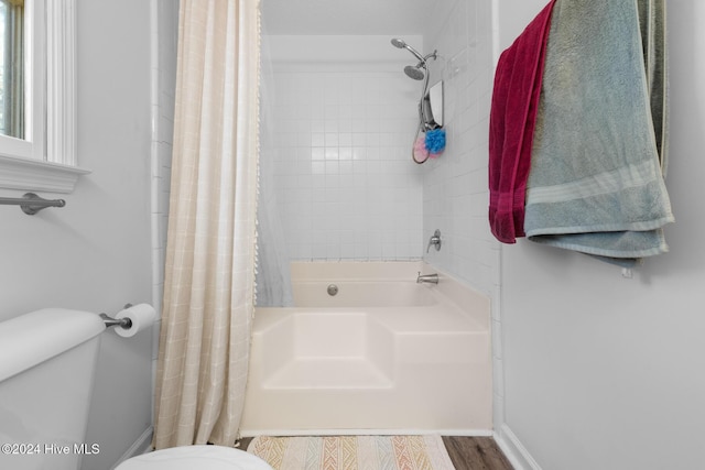 bathroom featuring wood-type flooring, shower / tub combo, and toilet