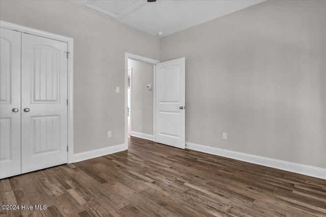 unfurnished bedroom featuring a closet, dark wood-type flooring, and ceiling fan