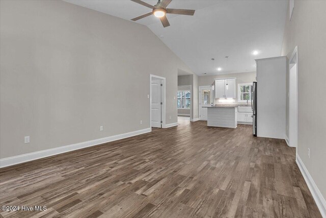 unfurnished living room featuring dark hardwood / wood-style floors, high vaulted ceiling, and ceiling fan