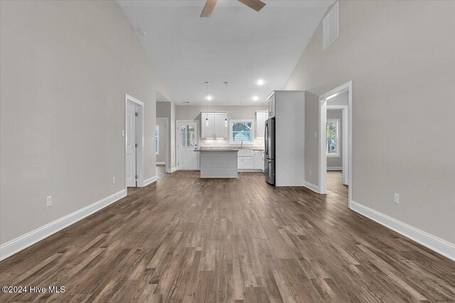 unfurnished living room with dark hardwood / wood-style floors, ceiling fan, and high vaulted ceiling