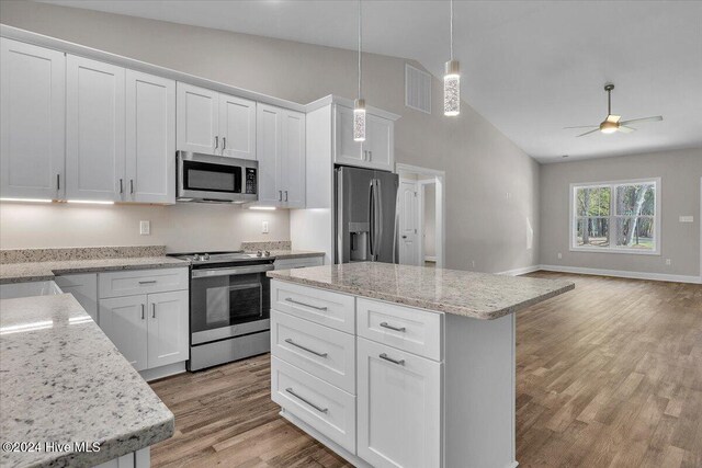 kitchen featuring white cabinets, appliances with stainless steel finishes, and lofted ceiling