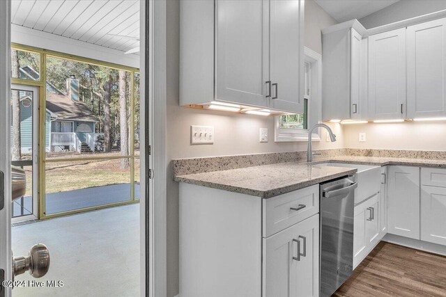 kitchen featuring light stone countertops, dark hardwood / wood-style flooring, stainless steel dishwasher, sink, and white cabinets