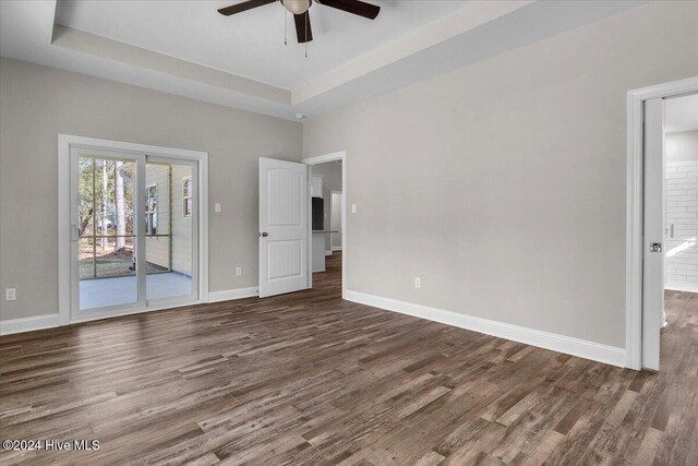 interior space featuring dark hardwood / wood-style floors, ceiling fan, and a tray ceiling